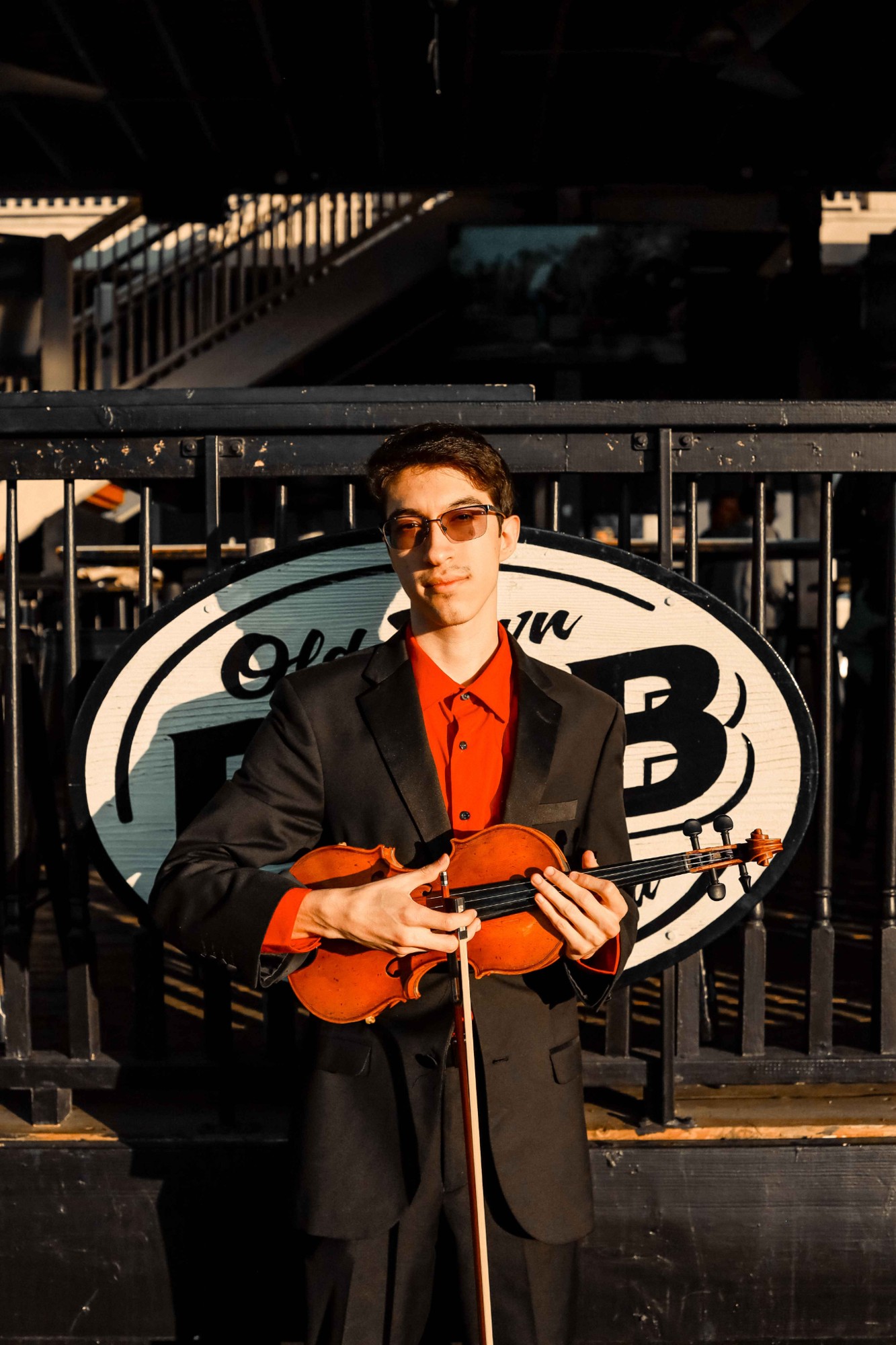 Marcus Cotton holding his violin in warm evening light